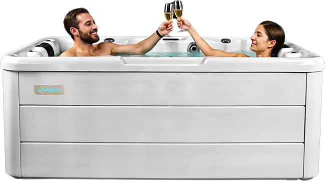 A man and a woman relax in a white hot tub hire, smiling and clinking champagne glasses together, enjoying exceptional service.